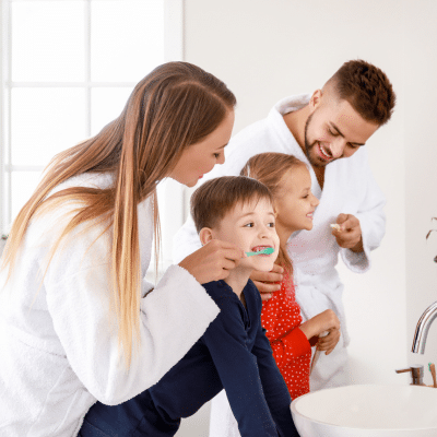 Mother and father brushing their kids teeth in the morning, representing family dentistry in ashburn
