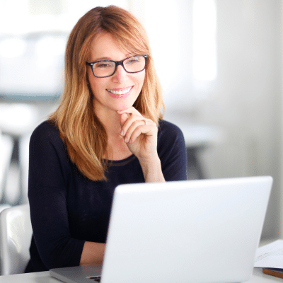 Woman smiling while working on a laptop, representing ashburn dentistry and ashburn dentistry by design's new website