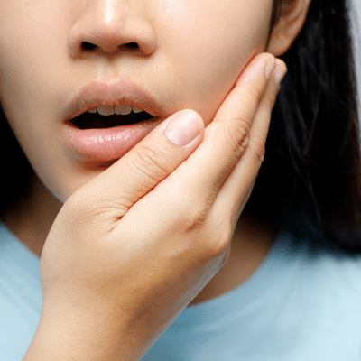 Woman holding her jaw in pain, representing what to do in a dental emergency