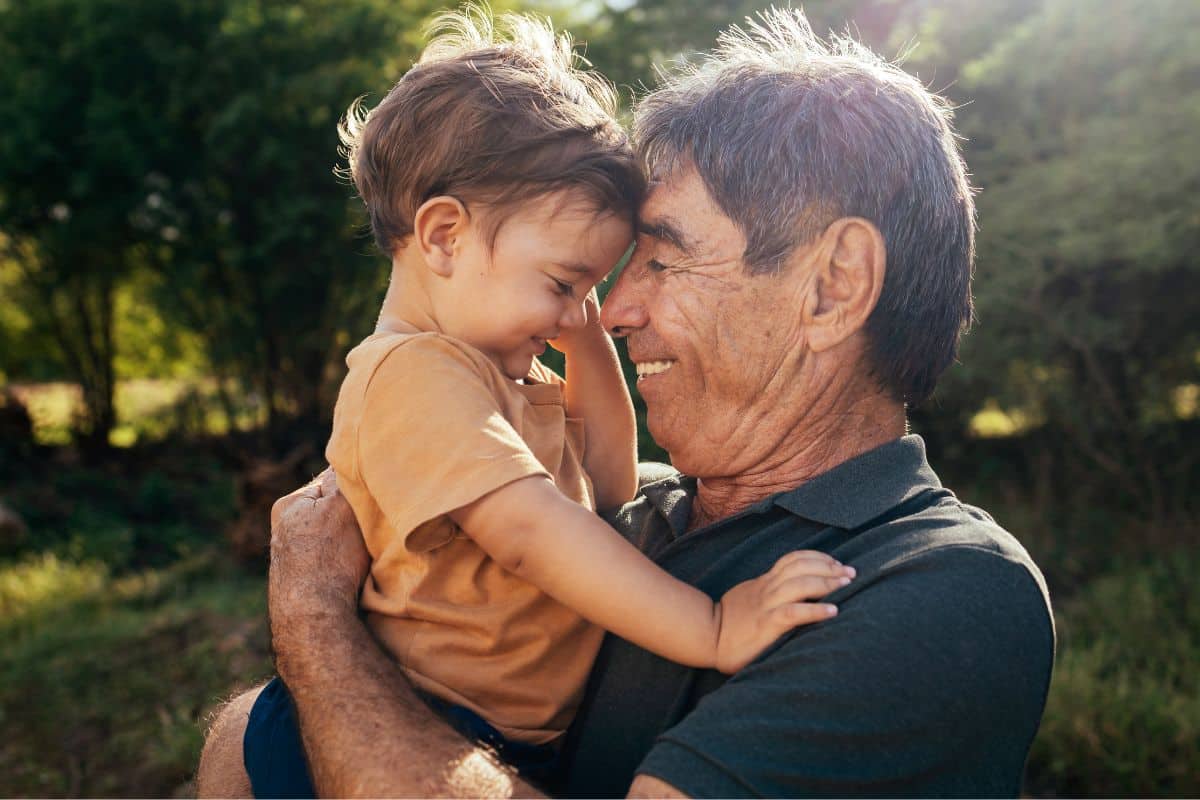 Grandfather playing with his grandson outdoors in a sunny park