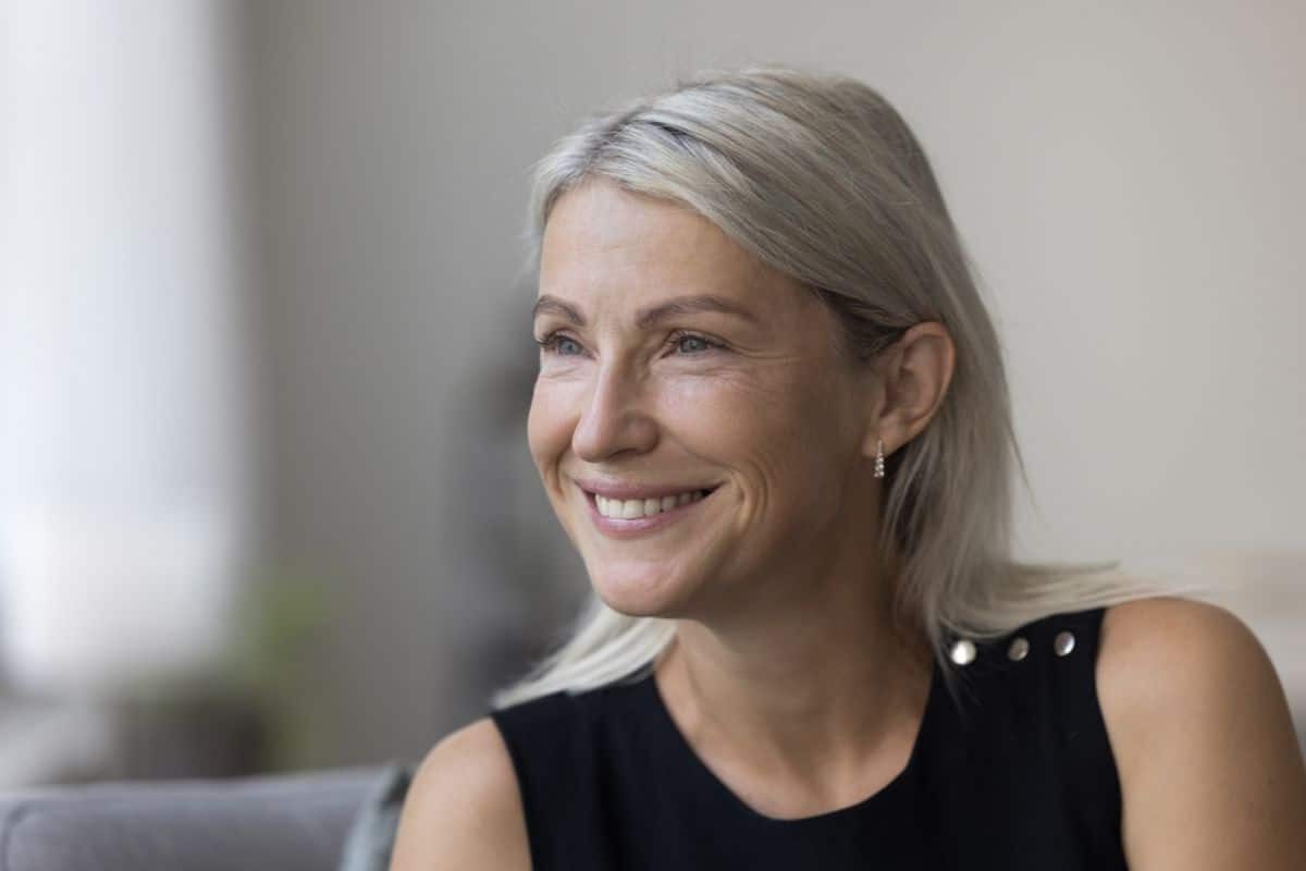 Candid portrait of a smiling mature blonde woman at home Happy mature blonde woman smiling with a thoughtful expression at home